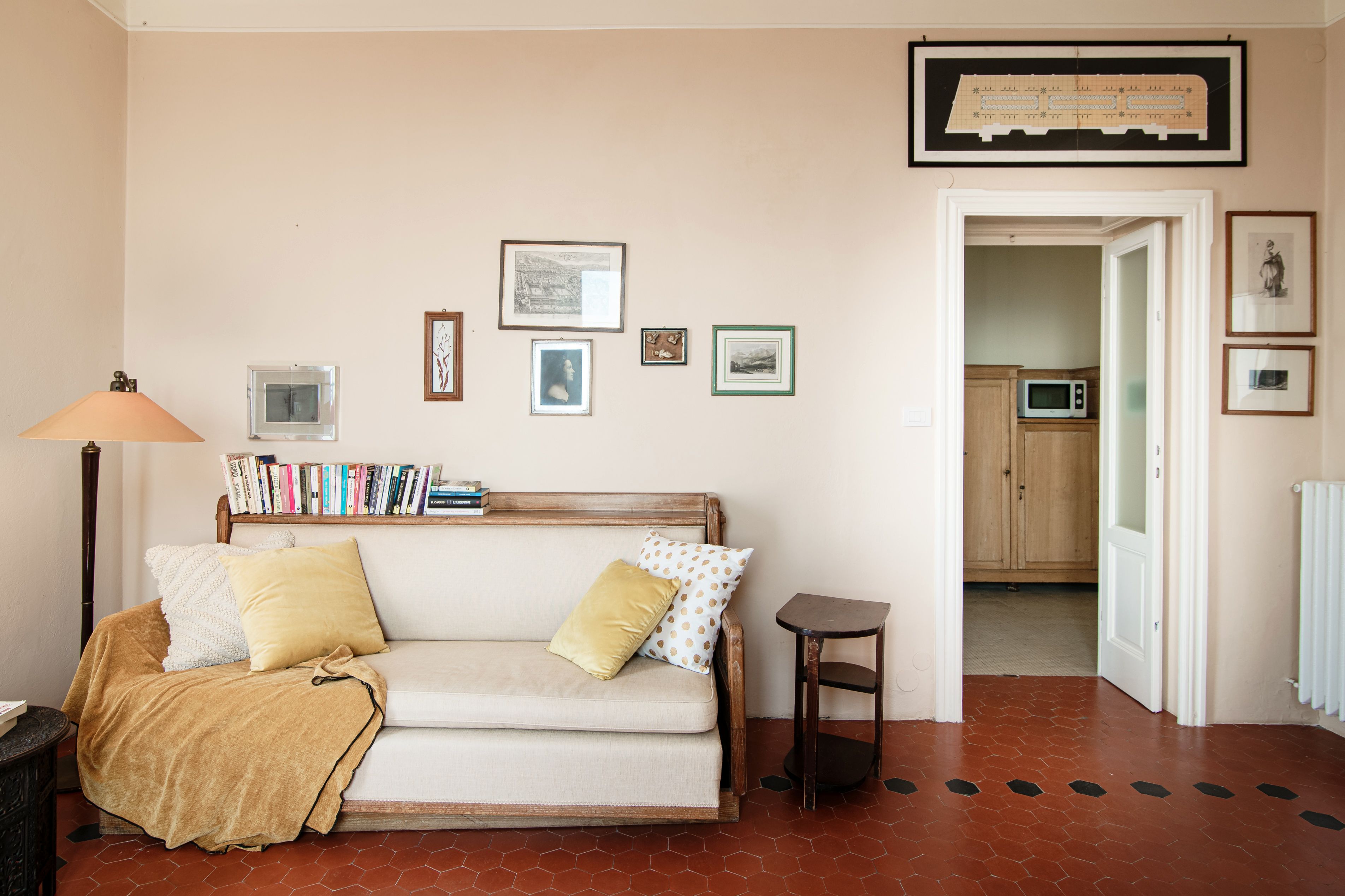 A living room with a sofa, a lamp, a bookshelf, and a framed picture on the wall.