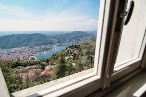 Vista desde una ventana a un paisaje urbano con río, montañas y cielo despejado.