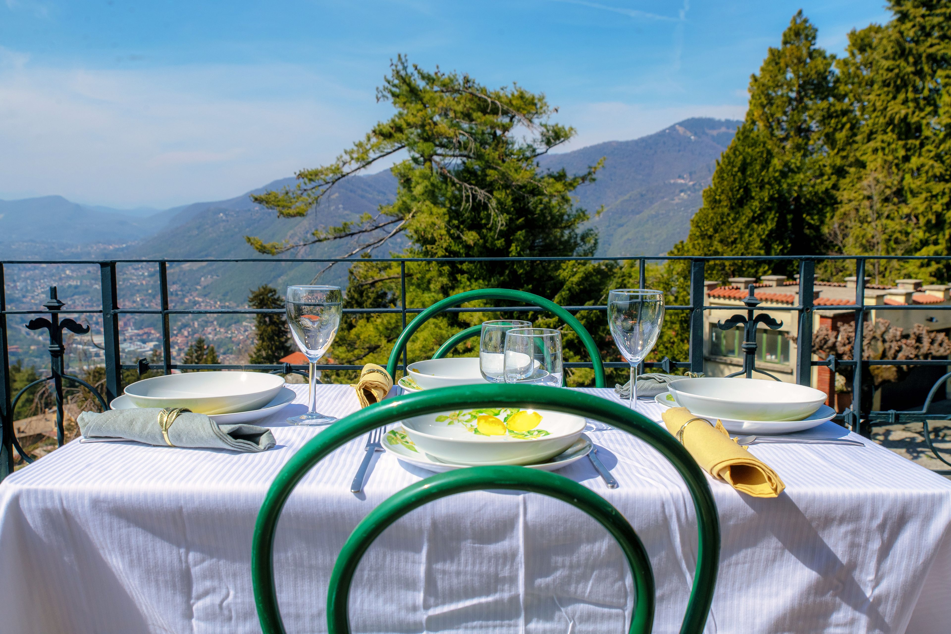 Une table dressée pour le dîner, avec une vue sur les montagnes et une ville en arrière-plan.