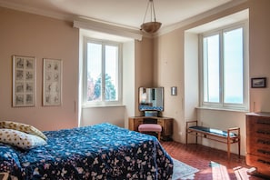 Un dormitorio con cama, cómoda, silla, espejo y obras de arte en la pared.