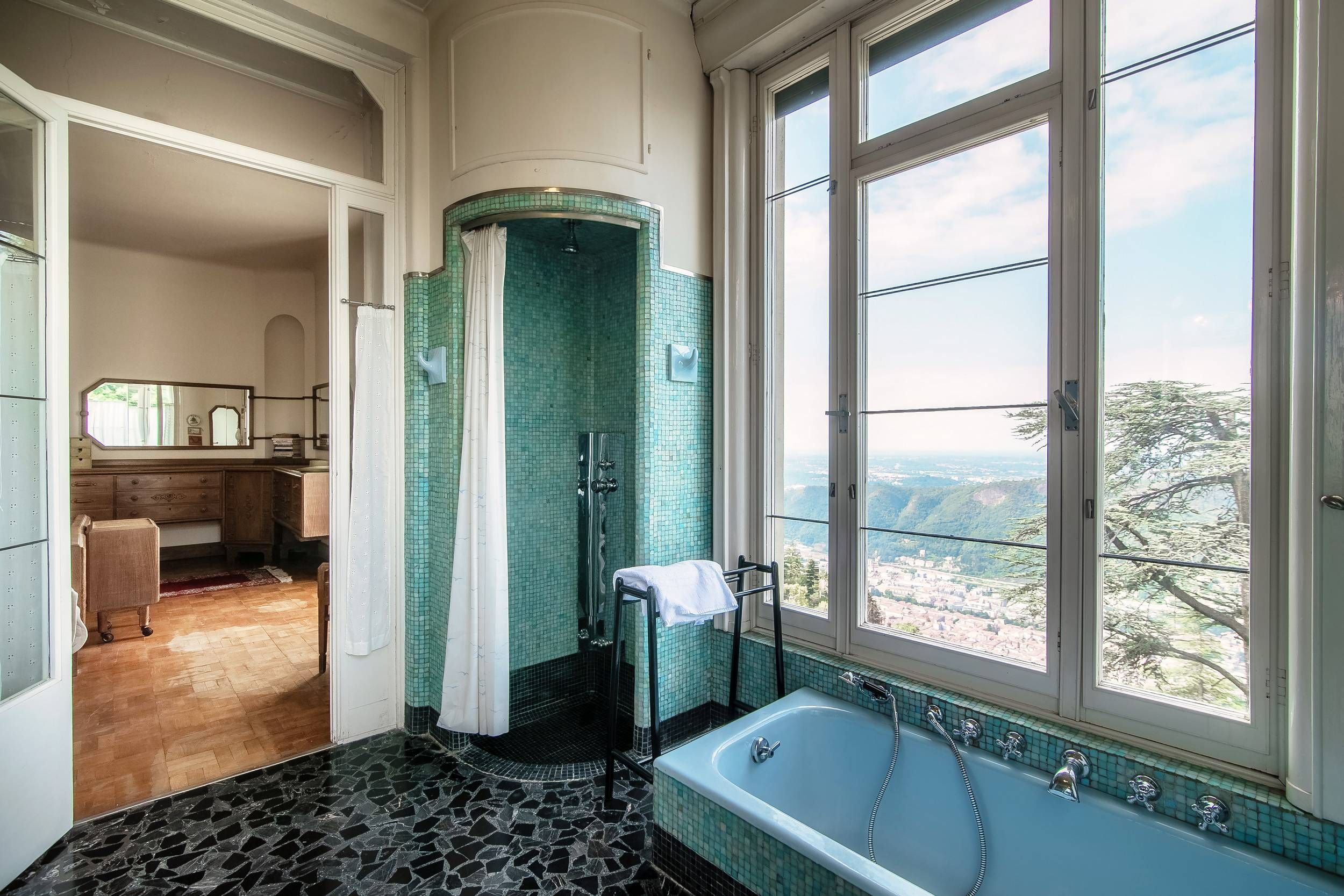 Une salle de bain dotée d’une grande baignoire, d’une douche et offrant une vue sur l’extérieur grâce à une grande fenêtre.
