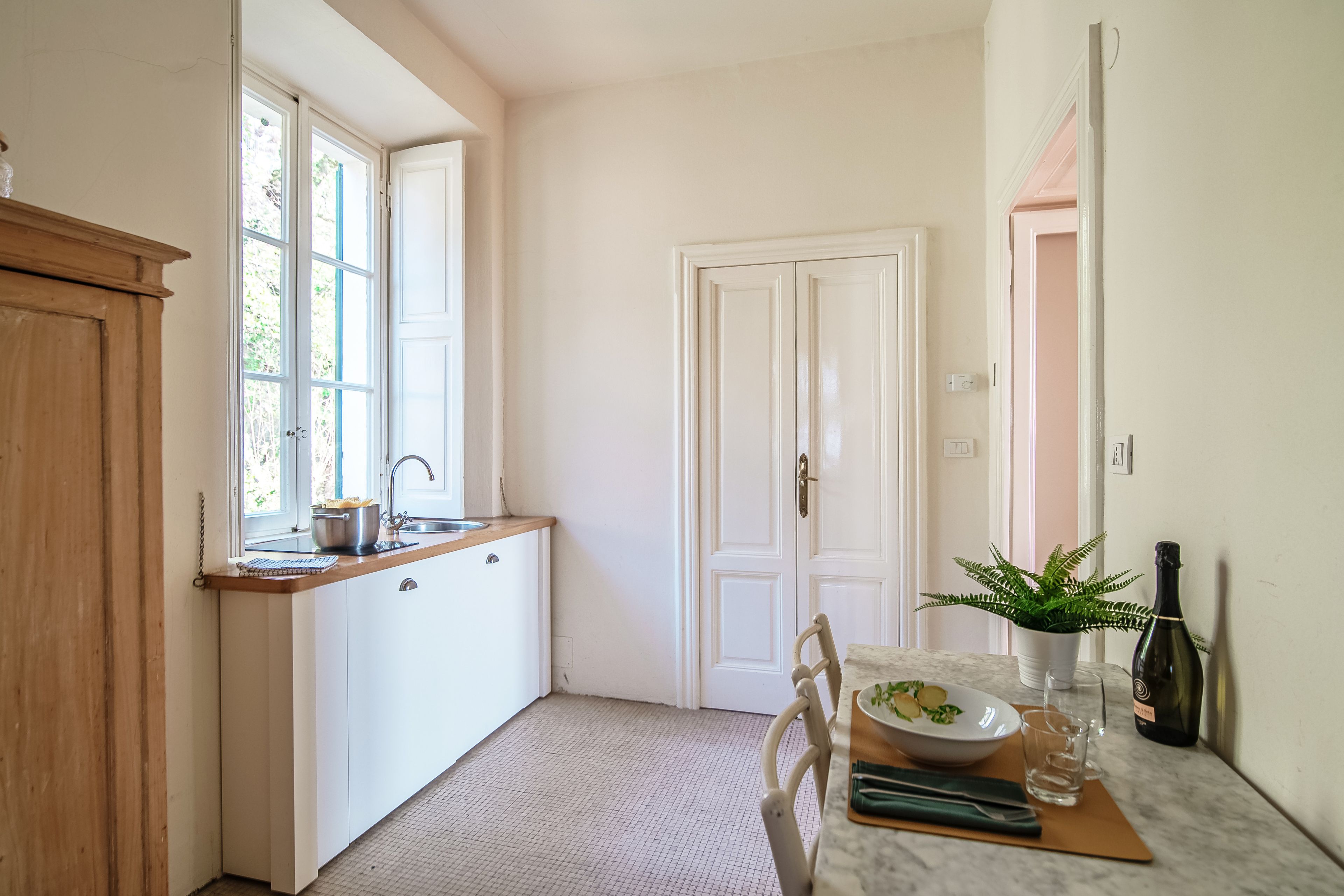 A compact kitchen with a window, a sink, and a dining area with a table set for two.