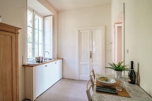 Cocina compacta con ventana, un lavamanos y comedor con una mesa dispuesta para dos.