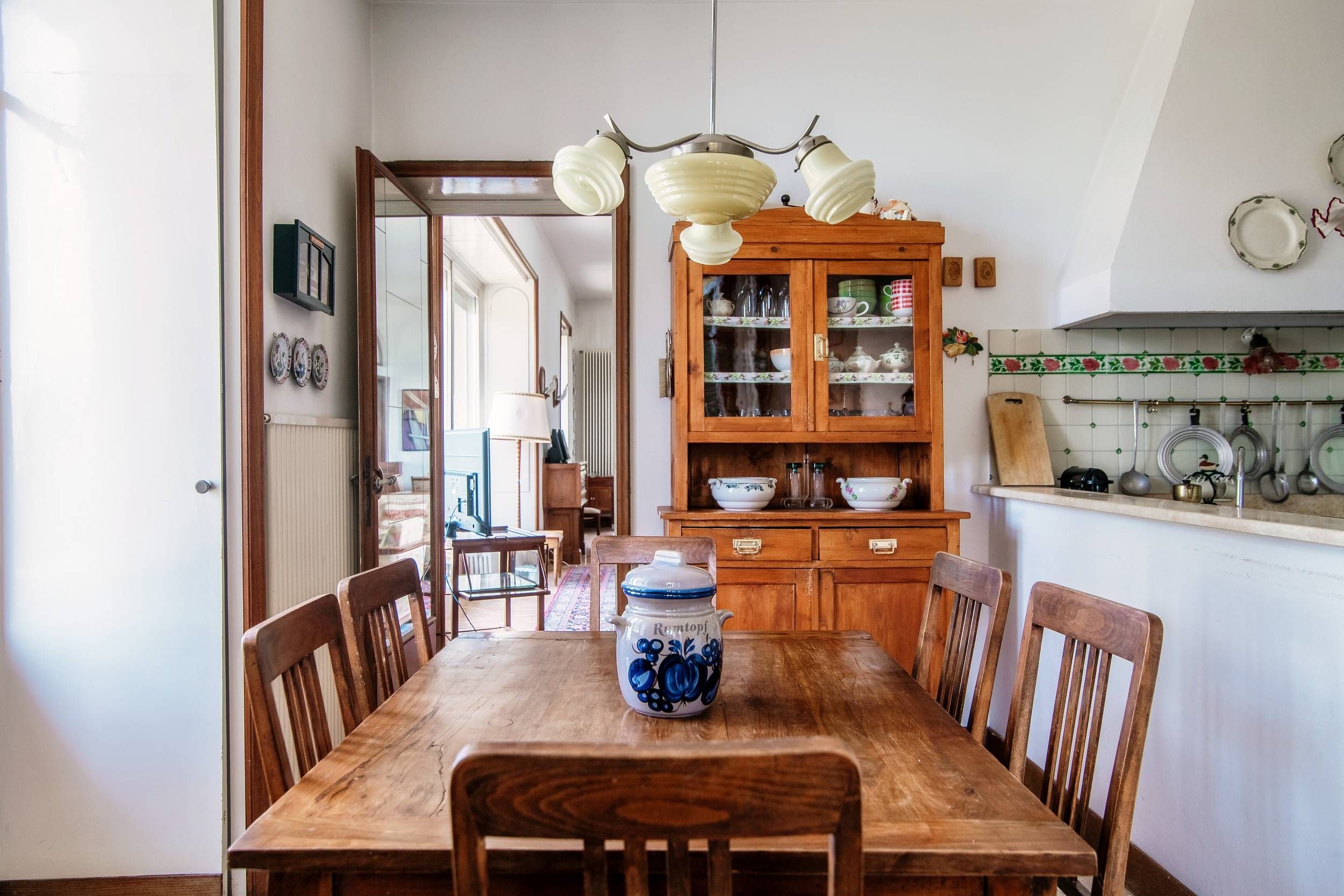 Ein Esszimmer mit Holztisch, Stühlen, einem Schrank mit Glastüren und einer Pendelleuchte.