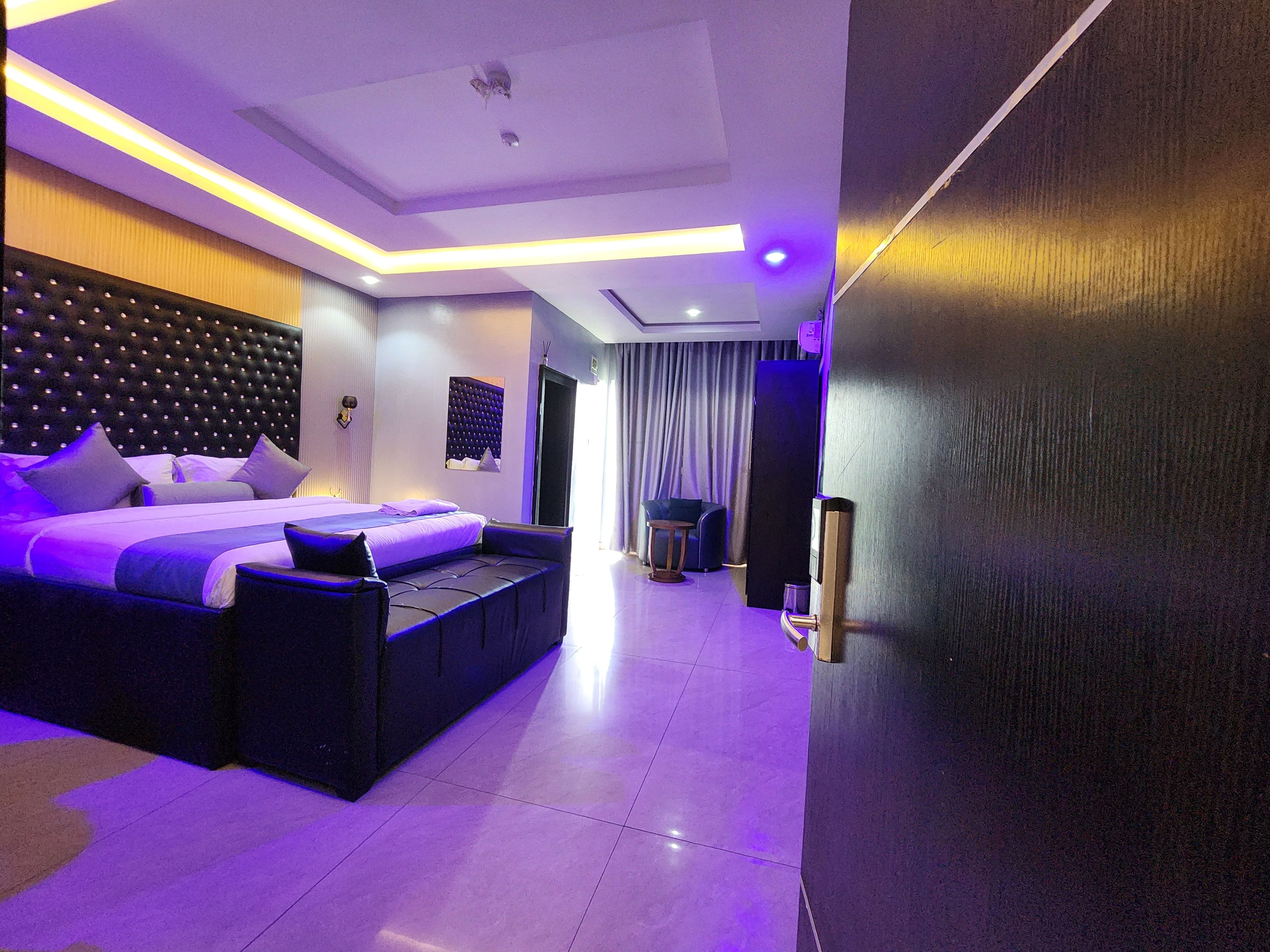Une chambre d’hôtel moderne avec un grand lit, un coin salon et une vue sur le couloir.
