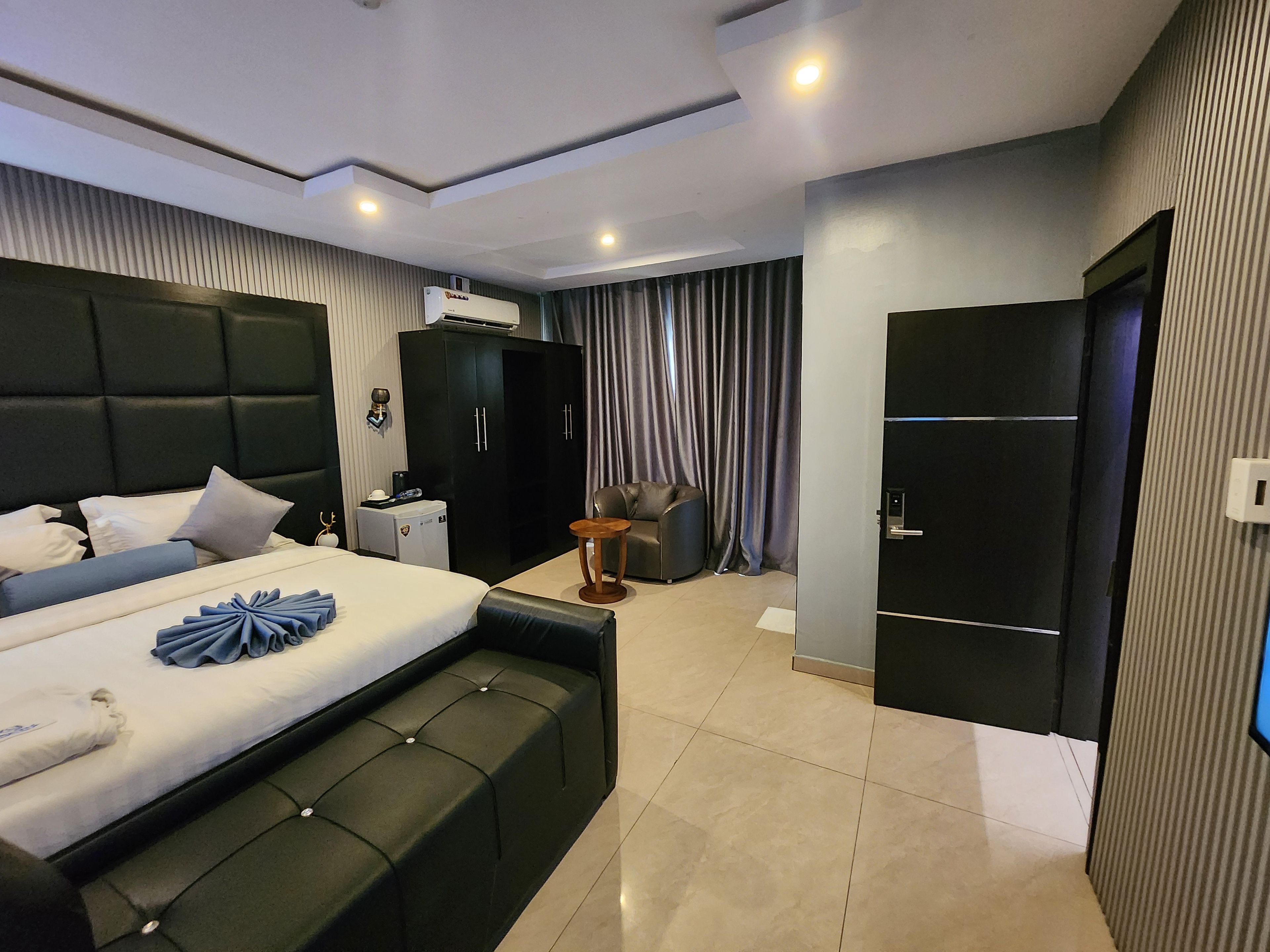 Ein modernes Hotelzimmer mit einem großen Bett, einem Kleiderschrank, einem Schreibtisch und einer Sitzecke.
