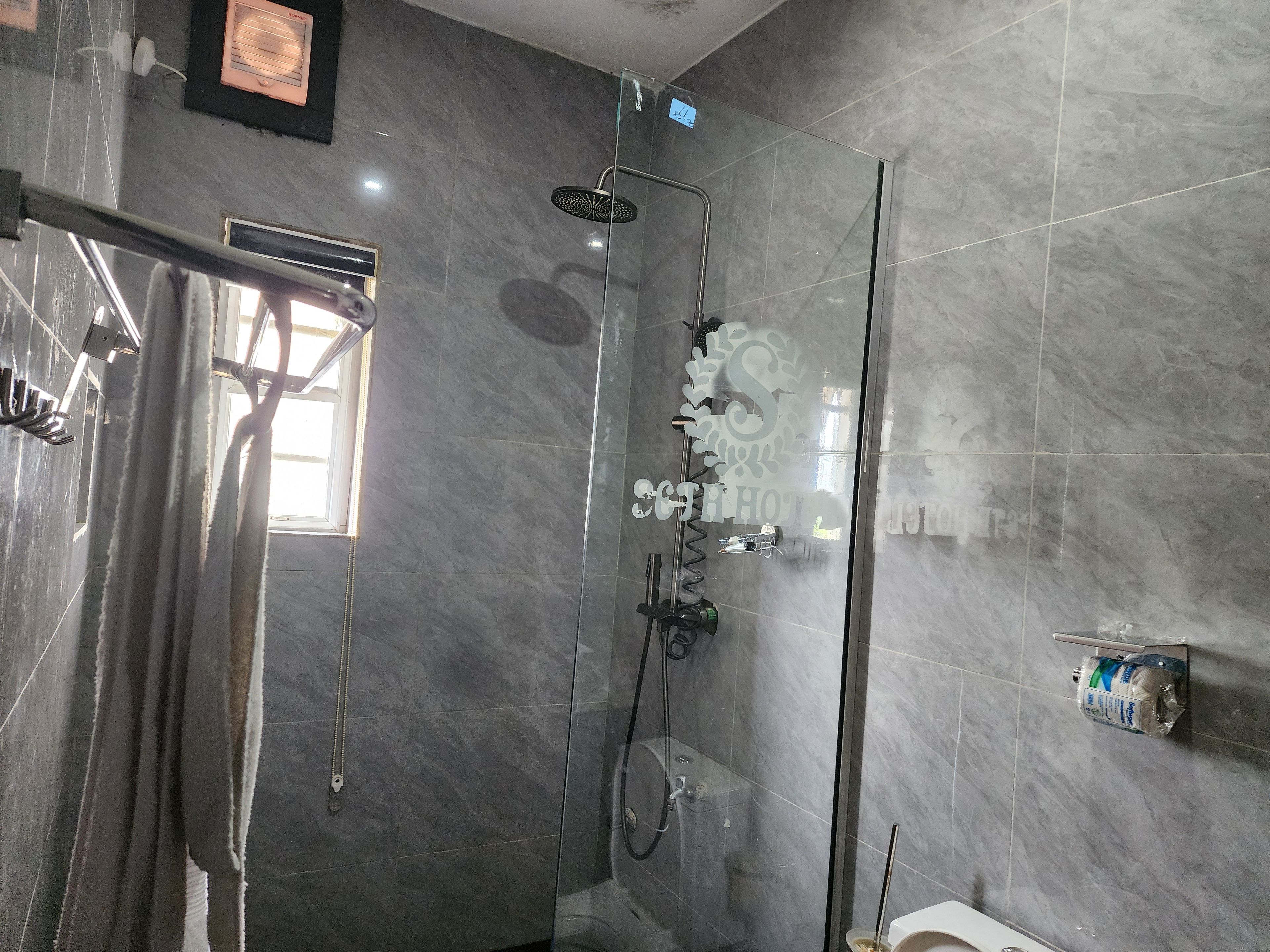 Un baño moderno con ducha envuelta en vidrio, un perchero visible y un inodoro.
