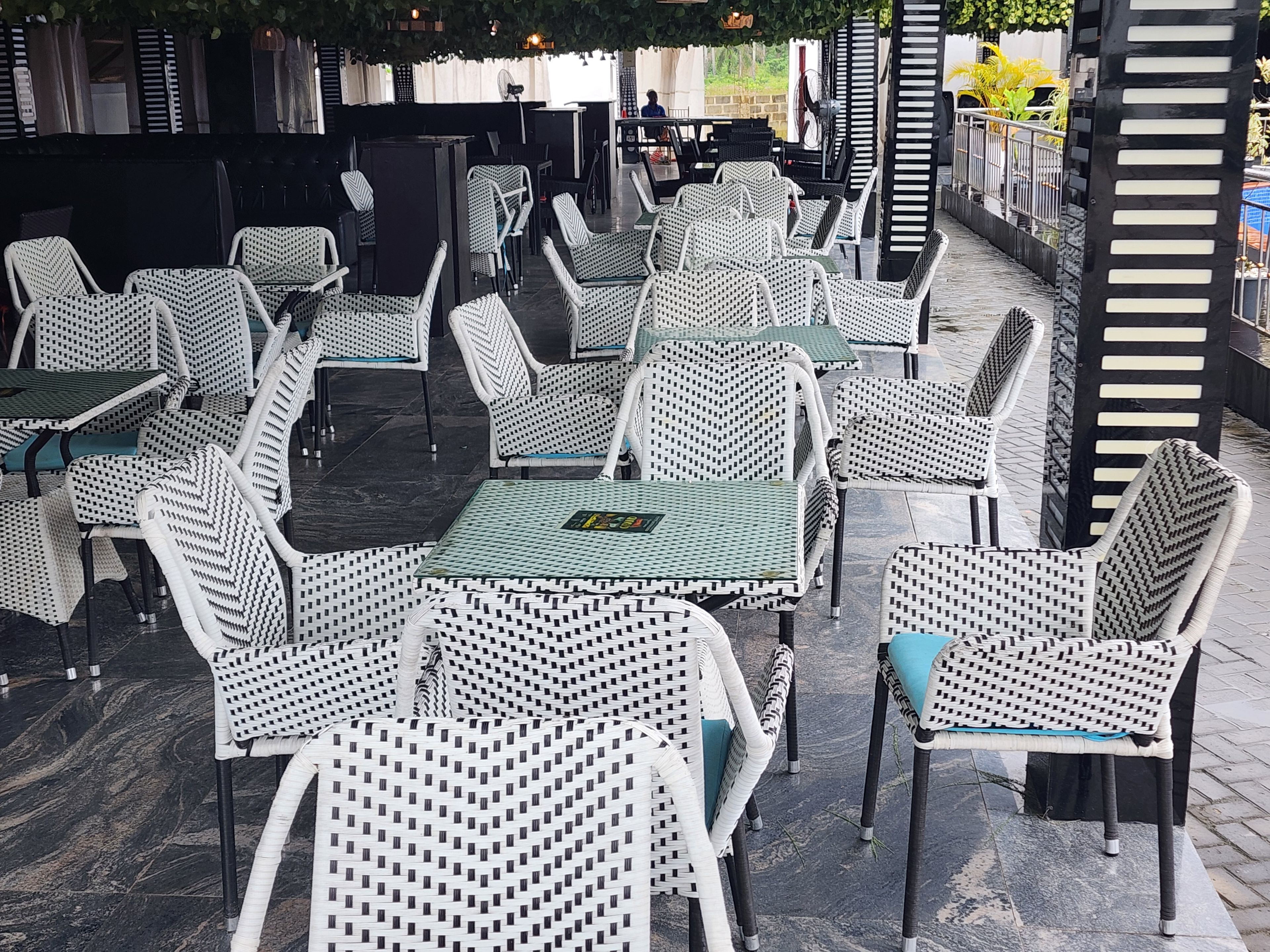 An outdoor seating area with white wicker furniture and green cushions.