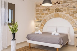 A bedroom with a stone wall, a bed with a headboard, a potted plant, and a bedside table. - Villa Licaj - Four Bedroom Villa, Sleeps 8 (Tragaki)