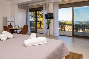Ein Hotelzimmer mit Bett, Esstisch mit Stühlen, Fernseher und Blick ins Freie.
