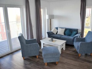A living room with a sofa, two armchairs, a coffee table, and a lamp. - 50.3.n North Berth (Wangerland)