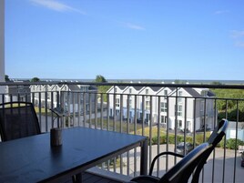 A balcony with a view of a row of houses and a clear sky.