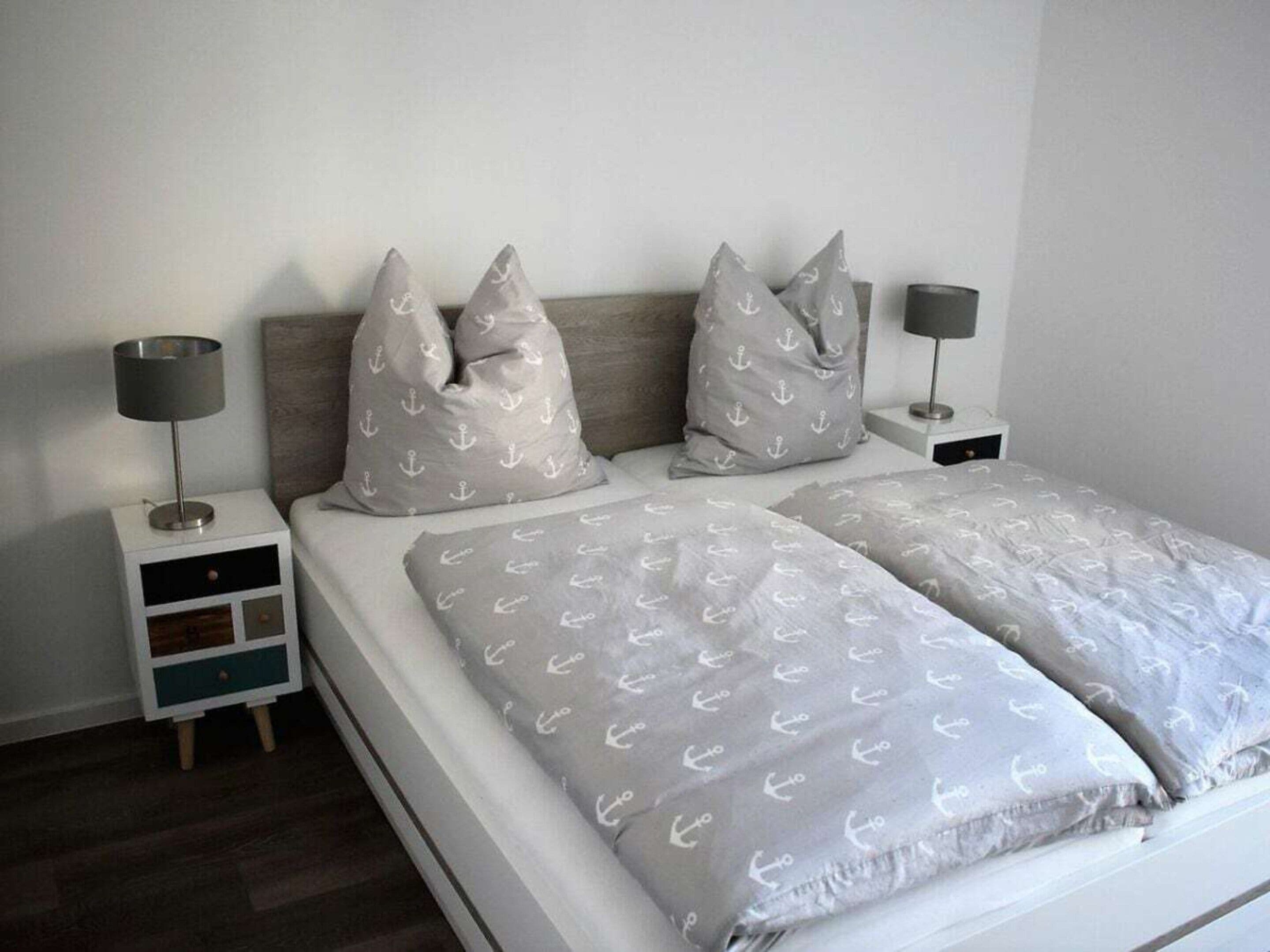 A bedroom with a bed, two nightstands, and two lamps.