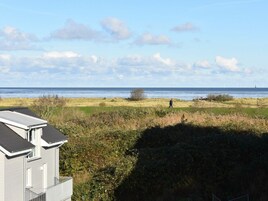 A coastal property with a view of the sea, a grassy field, and a building with a sloped roof.
