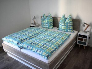 A double bed with a checkered bedspread, two bedside tables with lamps, and a headboard. - 50.3.n North Berth (Wangerland)
