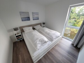 Ein Schlafzimmer mit einem Doppelbett, Nachttischen, einer Ablage und zwei an der Wand befestigten Bildern.