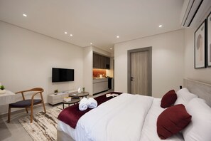 Ein Hotelzimmer mit Bett, Schreibtisch, Stuhl, Fernseher und einer Küchenzeile.