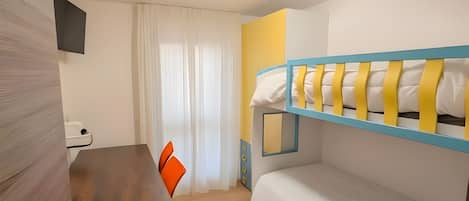 A room with a bunk bed, a desk with a chair, a window with curtains, and a flat-screen TV mounted on the wall.