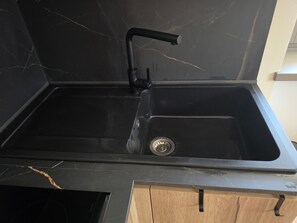 A kitchen with a black countertop, a black sink, and wooden cabinets. - Alba di Poggio al Sole Apartment in the Dolomites of Val di Sole (Mezzana)
