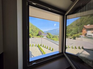 A window with a view of a paved area, a building, and a mountain. - Alba di Poggio al Sole Apartment in the Dolomites of Val di Sole (Mezzana)