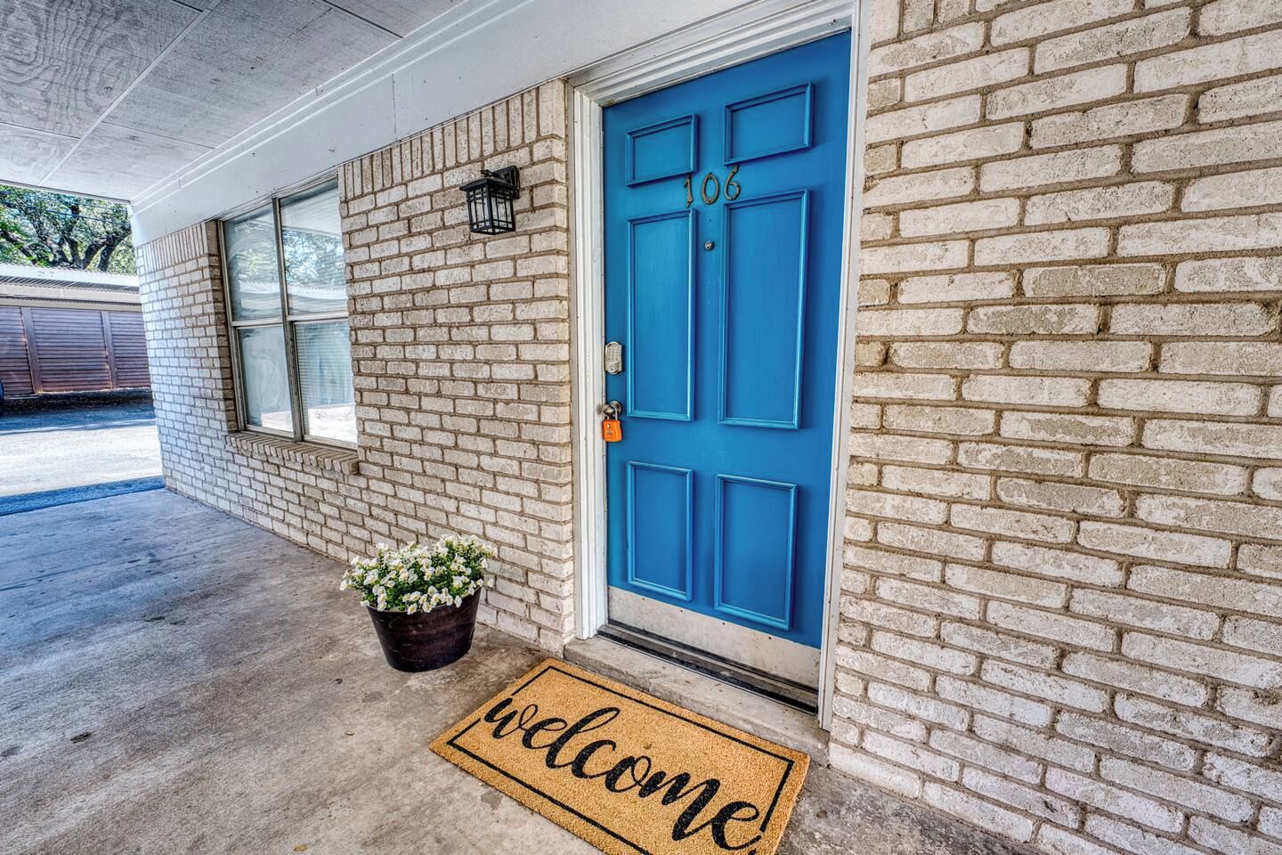 A building with a blue door, a welcome mat, and a potted plant.