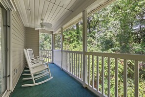 A covered porch with a rocking chair, a ceiling fan, and a view of a wooded area. - 3 bedroom third floor condo with Golf Course View! (Pawleys Island)