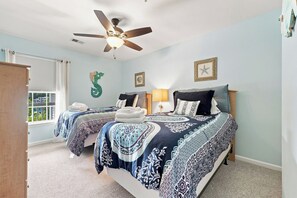 A bedroom with two beds, a ceiling fan, and a window with curtains. - 3 bedroom third floor condo with Golf Course View! (Pawleys Island)