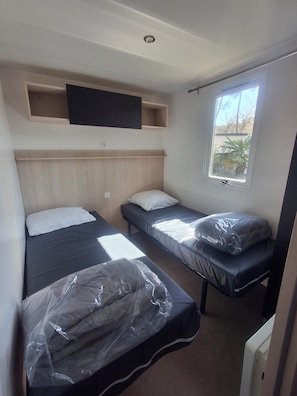 A room with two beds, a mounted TV, and a window with a view.