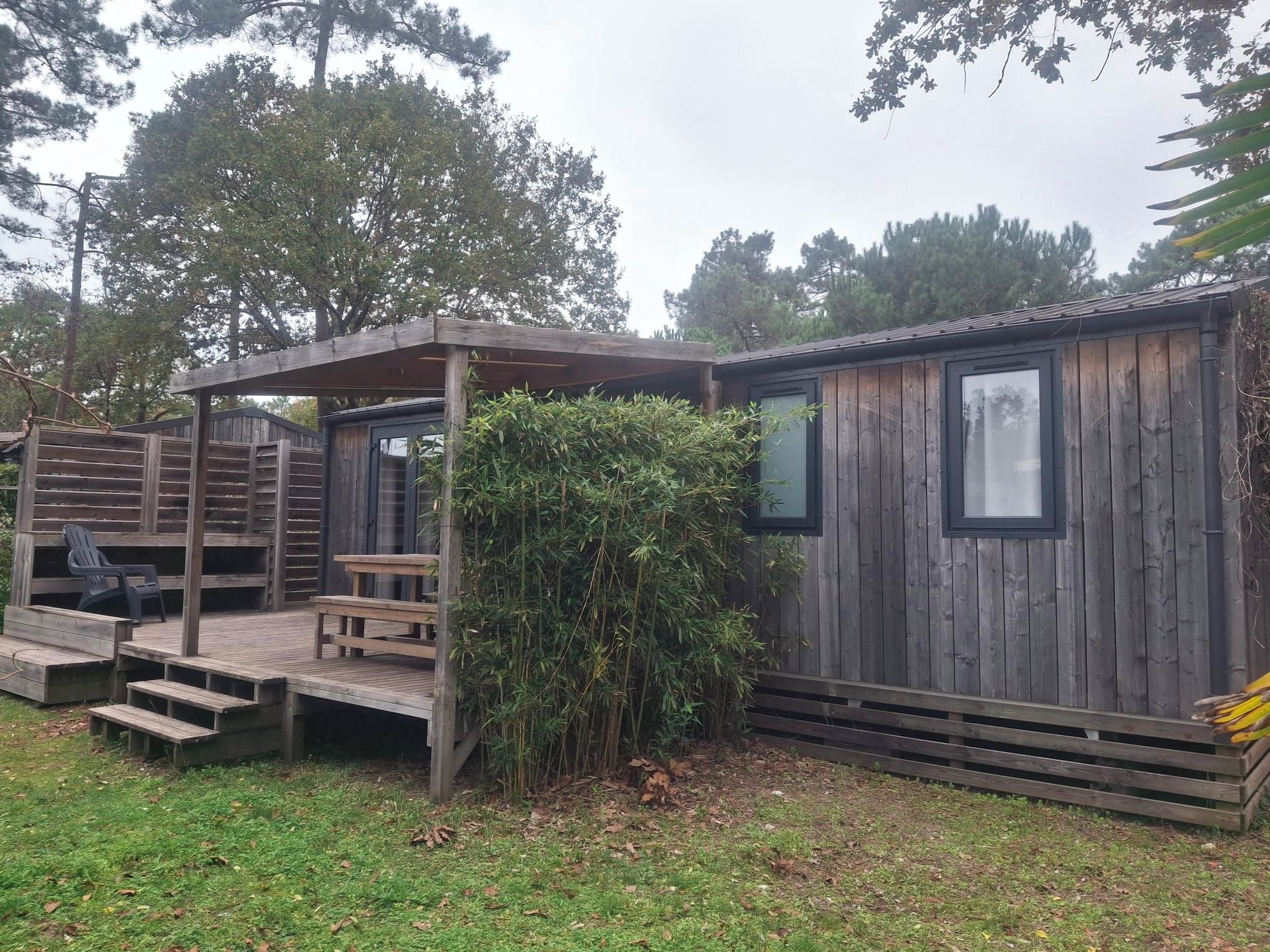 Una cabaña de madera con terraza y una zona de estar cubierta.