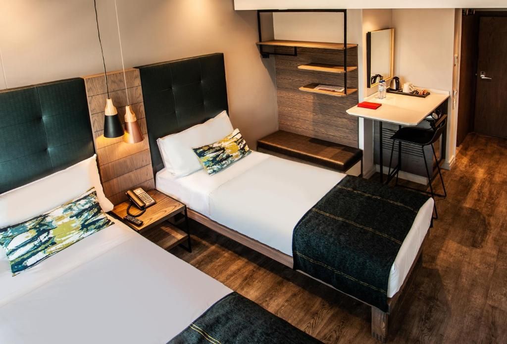 Een hotelkamer met twee bedden, een bureau, een stoel, een spiegel en een telefoon.