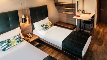 Een hotelkamer met twee bedden, een bureau, een stoel, een spiegel en een telefoon.
