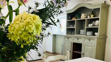 Een tafel met een tafelkleed met bloemen, een bord croissants en een bloevas.