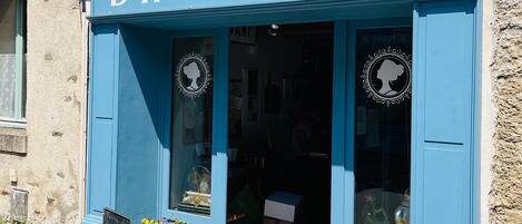 A storefront with the sign 'BROCANTE' and two potted plants outside.