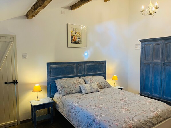 Ein Schlafzimmer mit einem Bett, zwei Nachttischlampen, einem Wandbild und einem Kleiderschrank.