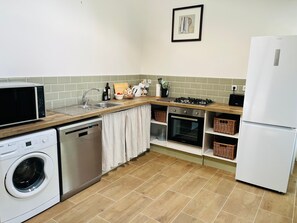 Eine kompakte Küche mit Waschmaschine, Mikrowelle, Backofen und Kühlschrank.