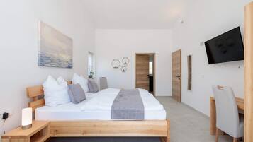 A modern bedroom with a wooden bed, a flat-screen TV, and a painting on the wall.