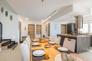 A modern kitchen with a central island, wooden doors, and a dining area with a breakfast setting. - Villa With Modern Living in Farini (Visnjan)