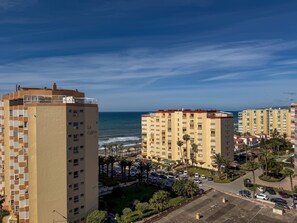 Ein Küstenwohngebiet mit Hochhäusern, einem Parkplatz und Blick auf das Meer.