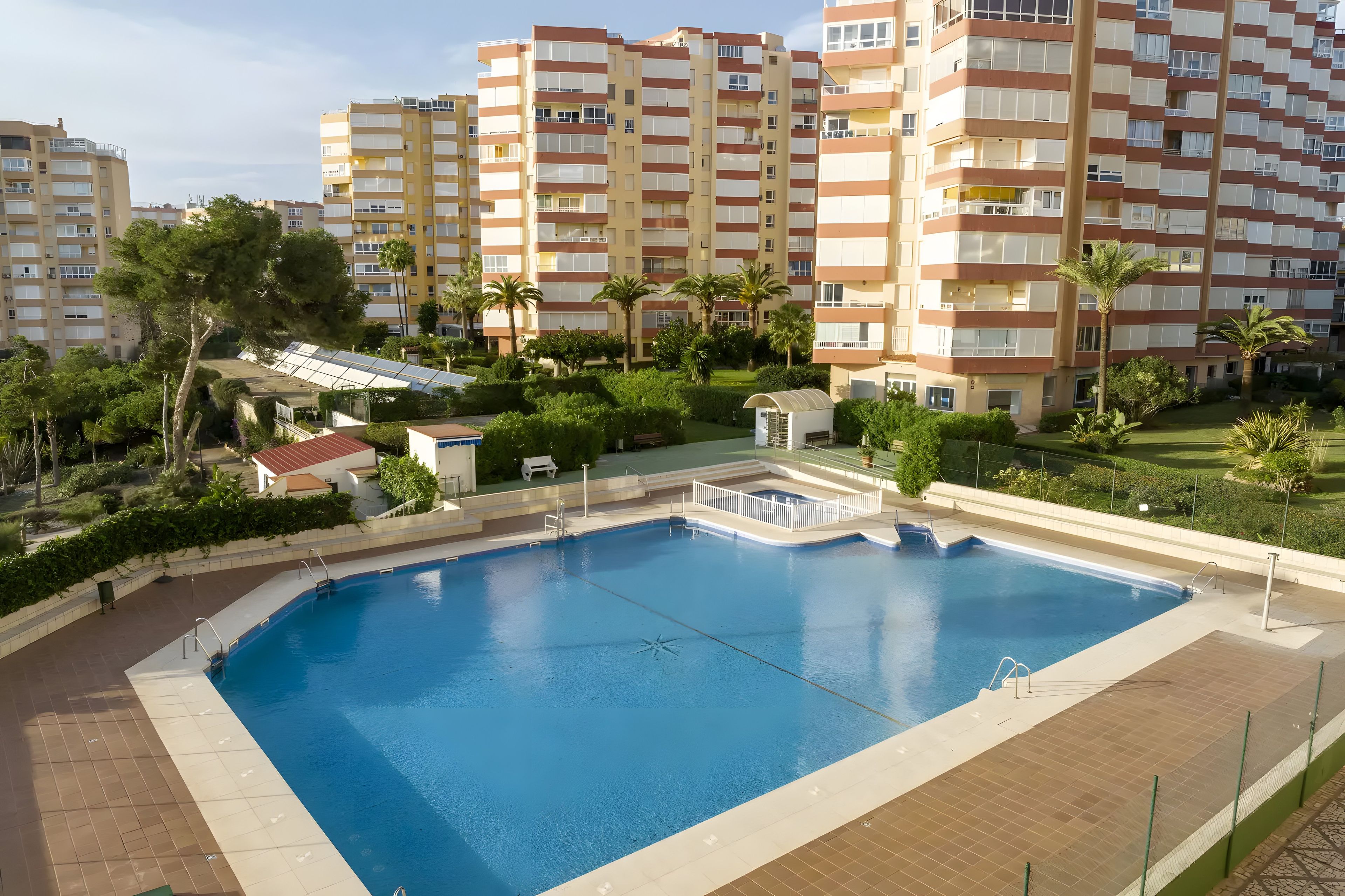 A swimming pool surrounded by greenery and residential buildings.