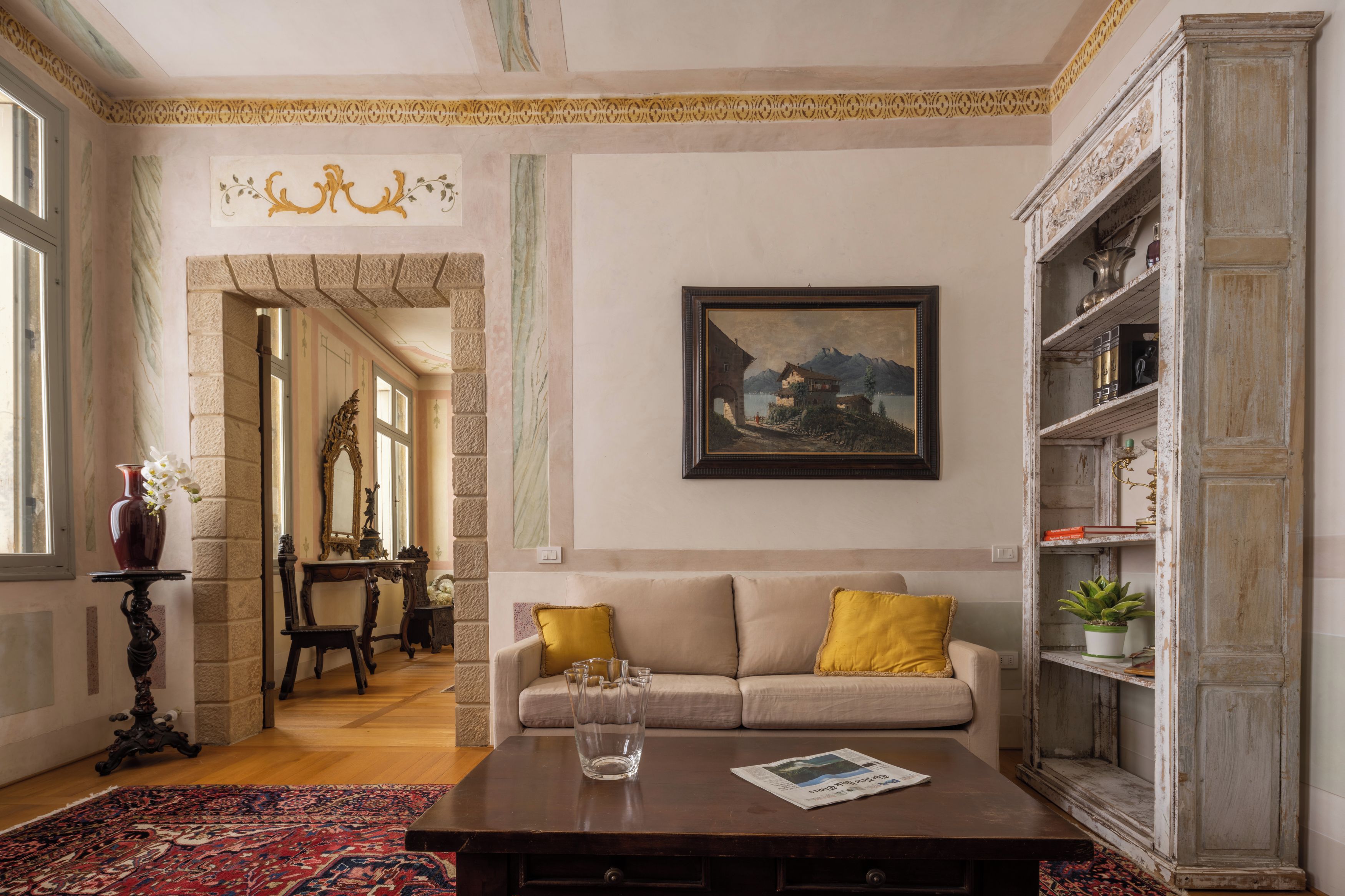 Una habitación con sofá, mesa de centro, un cuadro y una estantería.