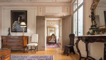 A spacious room with a large mirror, a wooden dresser, a chair, and a patterned rug.