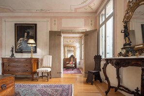 A spacious room with a large mirror, a wooden dresser, a chair, and a patterned rug. - Palazzo Benassi Nobile: Dimora nel Cuore di Asolo (Asolo)
