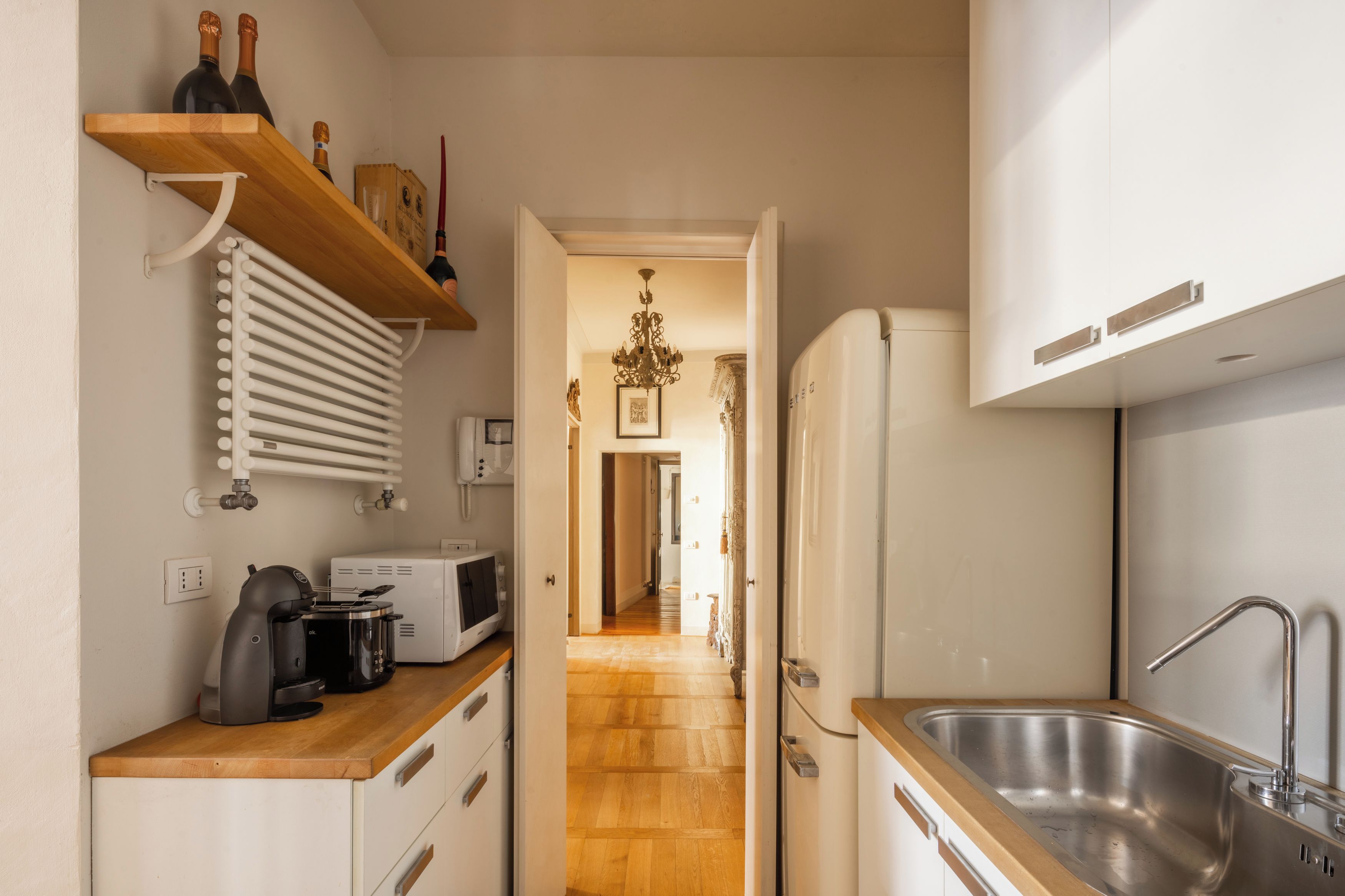 Une cuisine avec un plan de travail en bois, un réfrigérateur blanc, un évier en acier inoxydable et un four à micro-ondes.