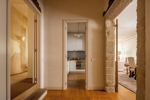 Un pasillo que conduce a una cocina con horno empotrado y un comedor con mesa y sillas.