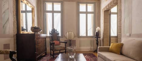 A room with a wooden coffee table, a sofa, a chair, a dresser, and a window with a view.