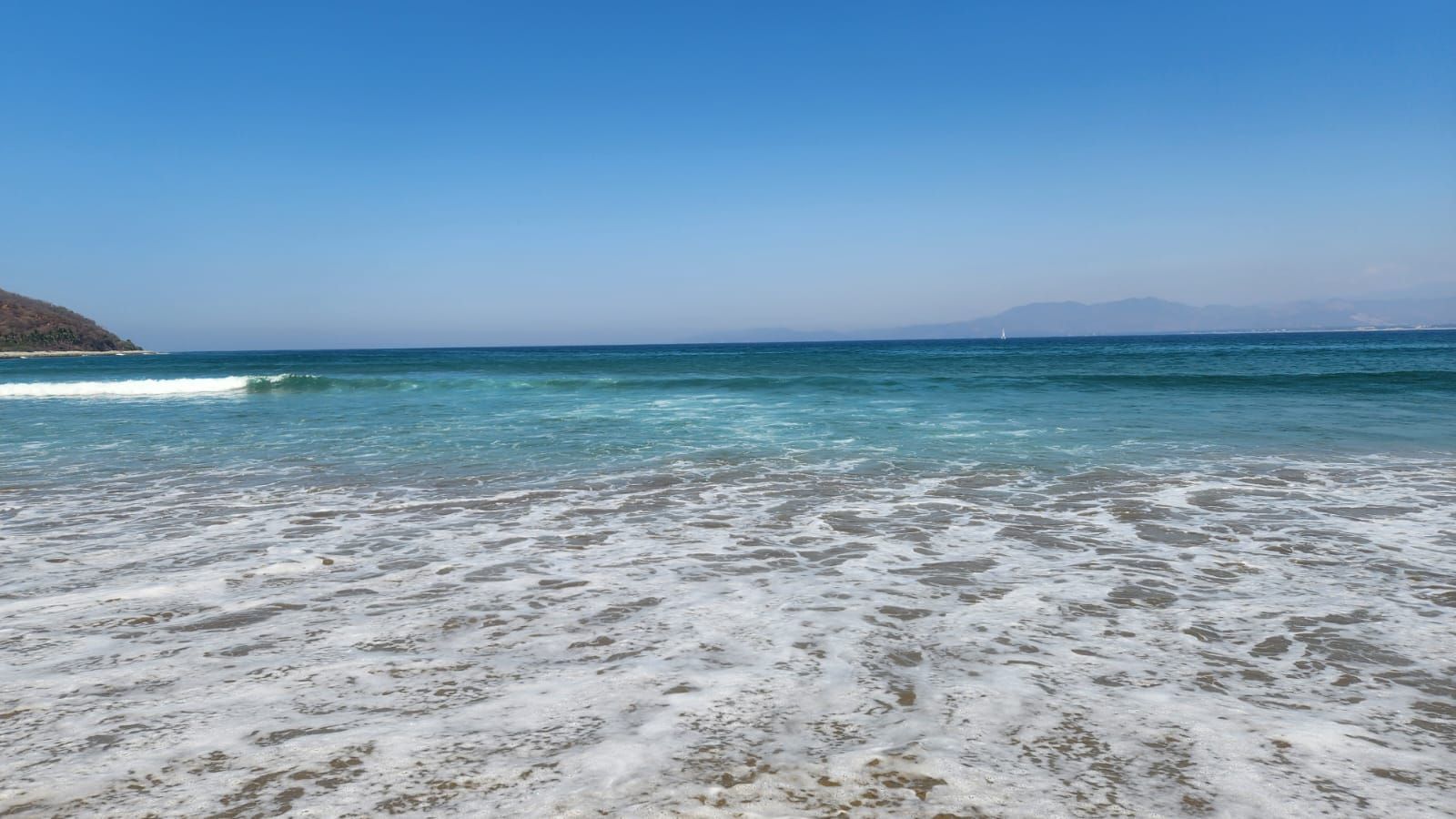 A beach with clear water and a sandy shore.