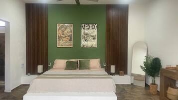 A bedroom with a large bed, two wall-mounted lamps, a ceiling fan, and two framed pictures.