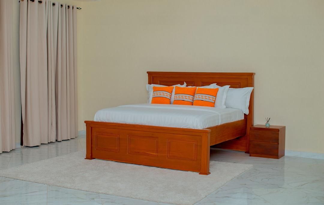 A bedroom with a wooden bed, white bedding, and orange pillows.