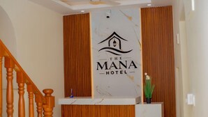 A reception desk with a logo for 'The Mana Hotel' and a wooden panel wall. - The Mana Hotel (Zanzibar)
