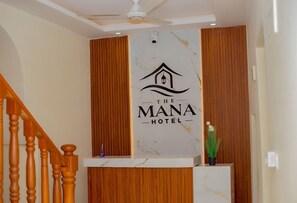 A reception desk with a logo for 'The Mana Hotel' and a wooden panel wall. - The Mana Hotel (Zanzibar)